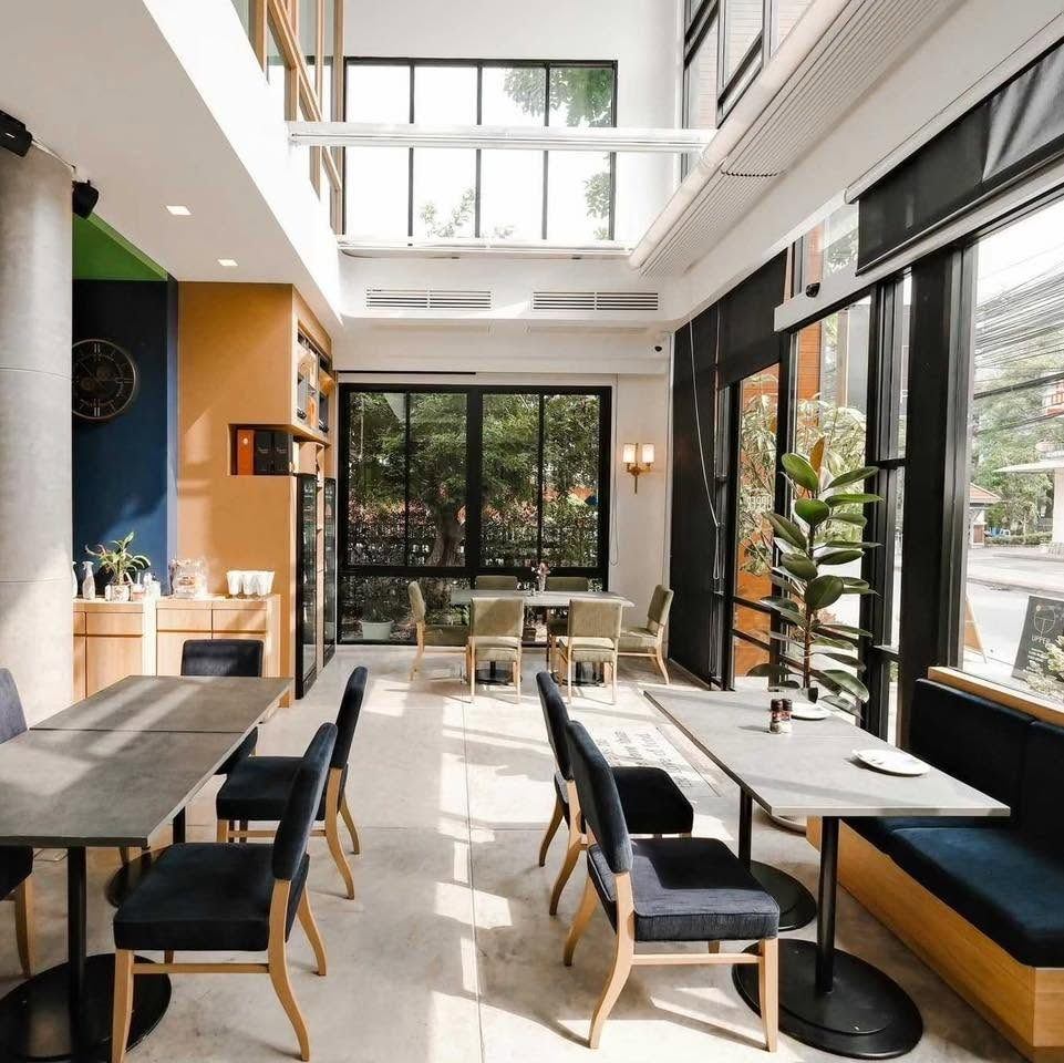 The bright dining room at UPPER·T with tall windows and garden views