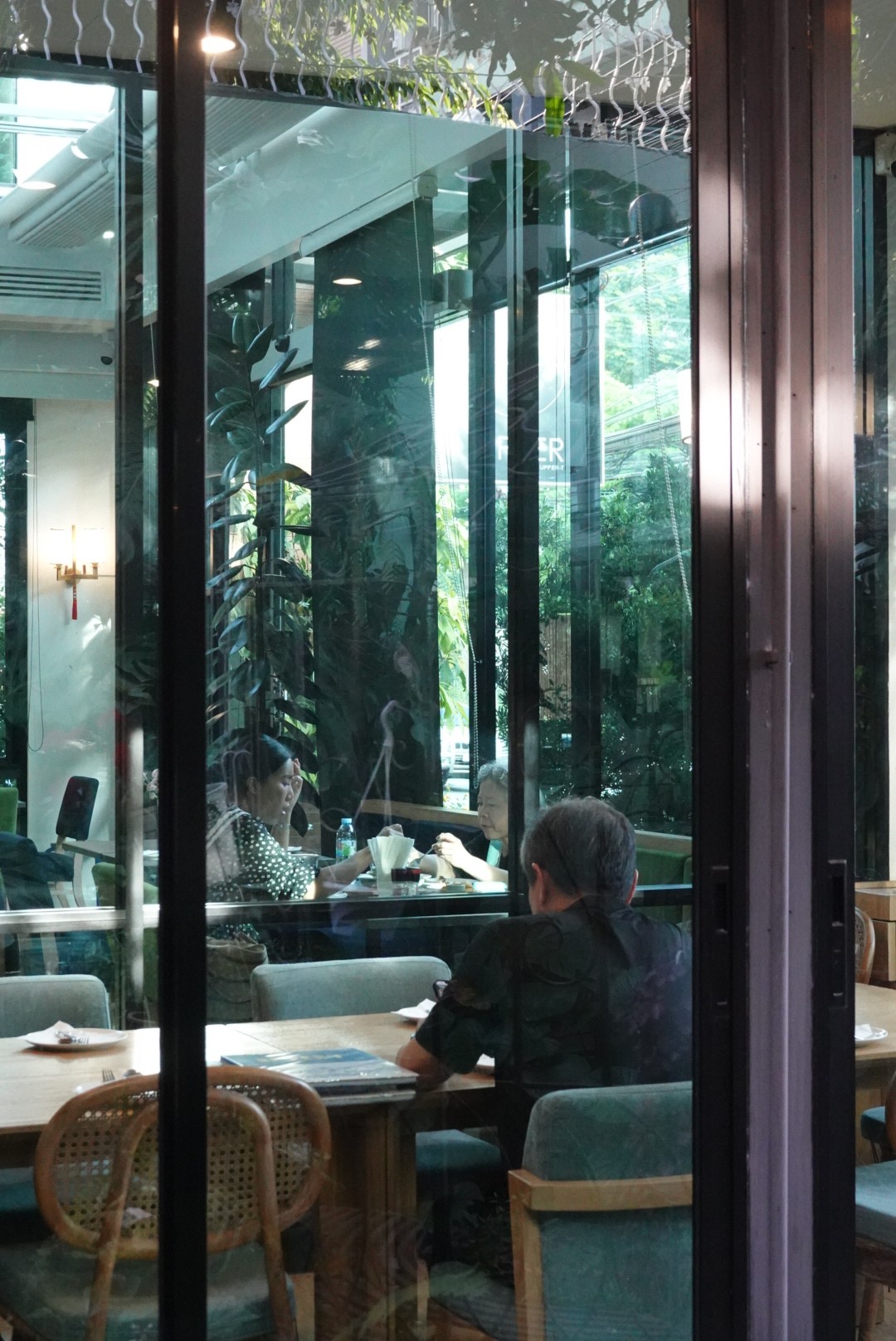 Guests dining at UPPER·T, seen through the garden windows